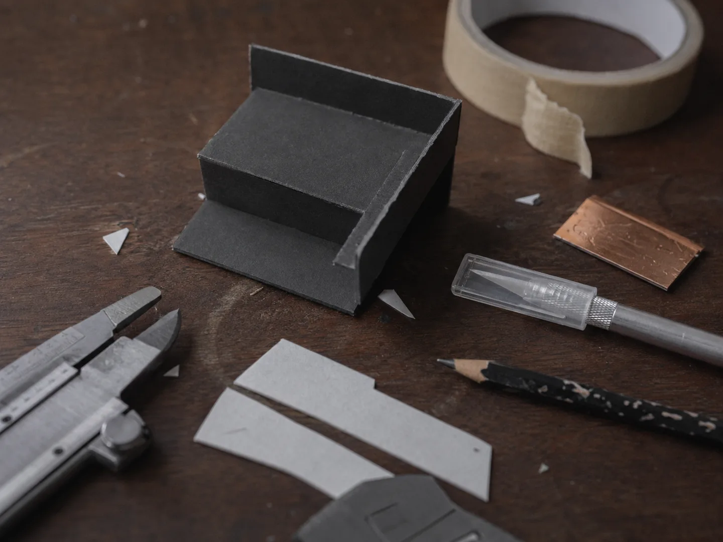 Studio tools and copper offcuts arranged on a dark work surface.